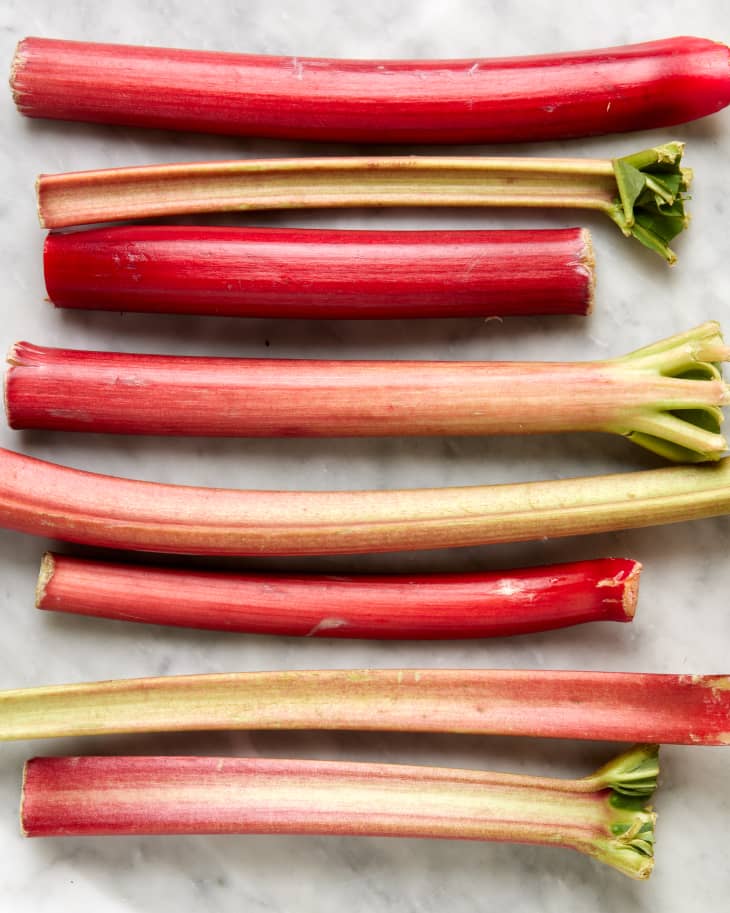 a shot of rhubarb plant in sliced halves lined from top to bottom on a marble background