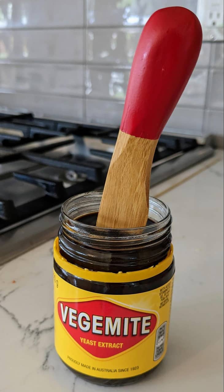 Vegemite on countertop with spoon inside container.