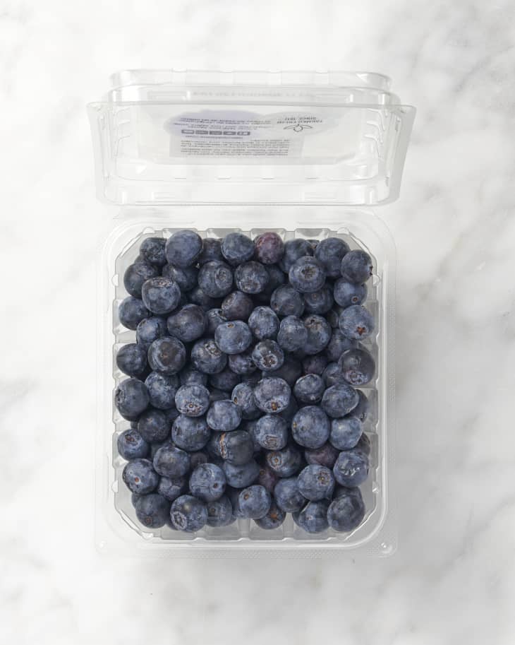 overhead shot of blueberries on marble surface in a plastic container