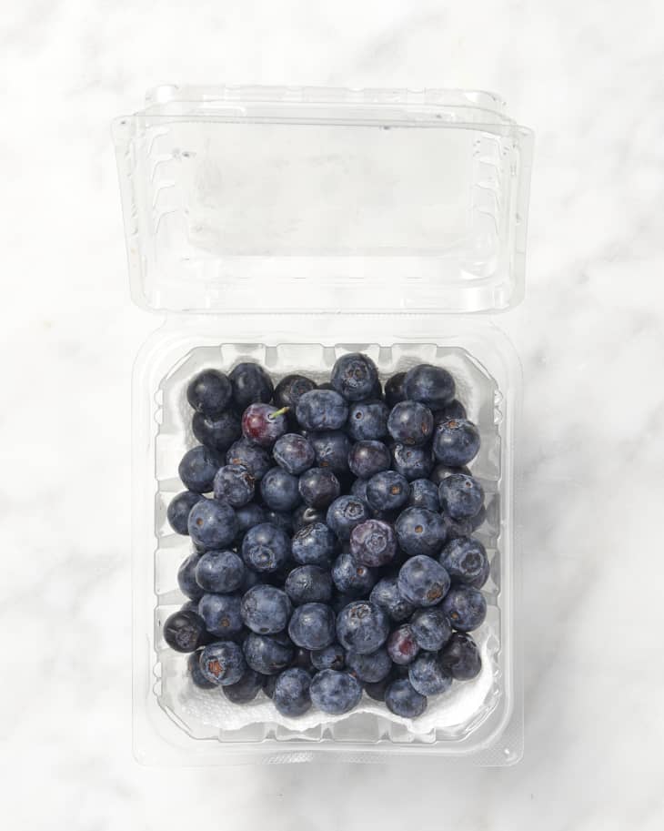 overhead shot of blueberries on marble surface in a container lined with paper towels
