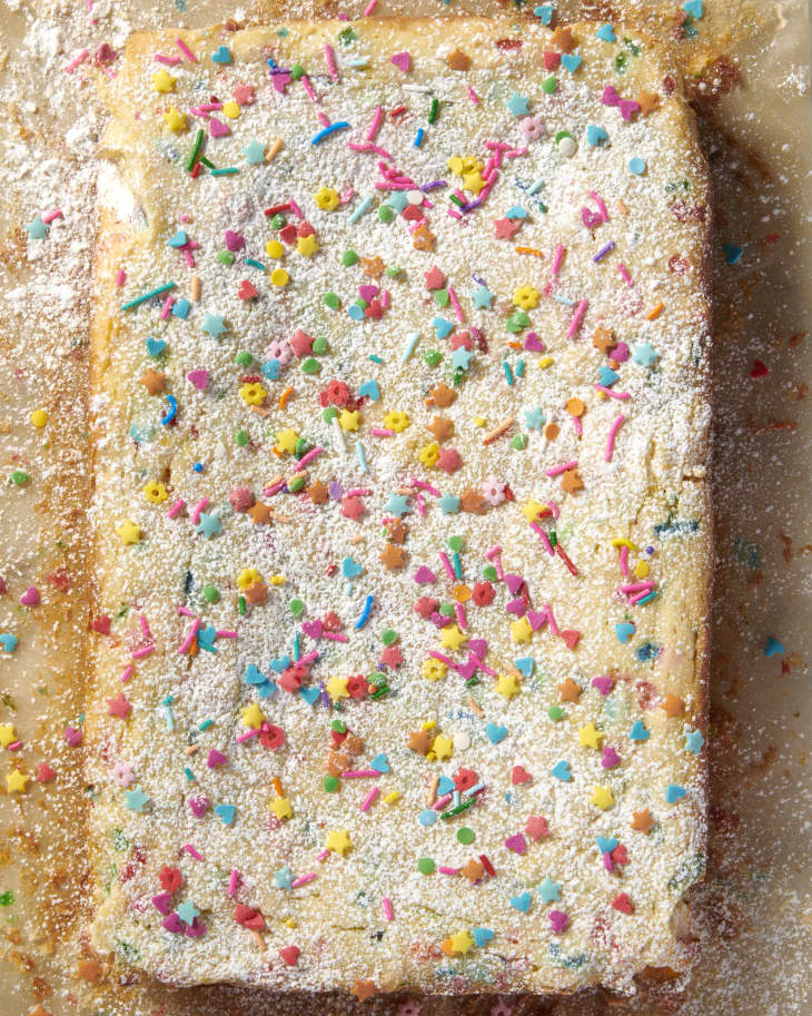 overhead shot of gooey butter cake with sprinkles and powder on a baking sheet