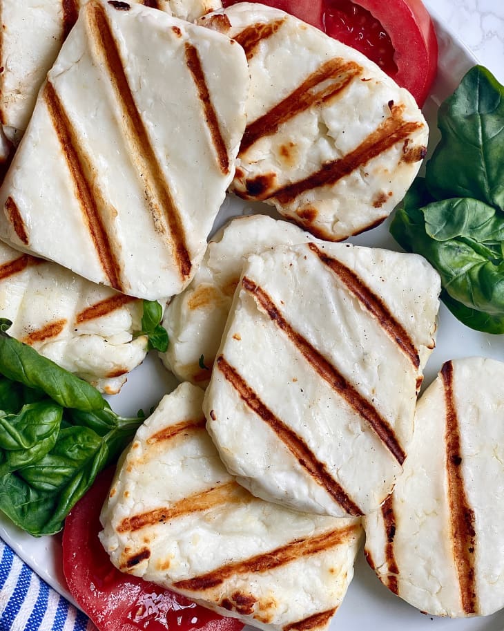 A plate of grilled halloumi, tomatoes, and basil