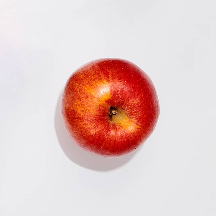 A gala apple on a white surface.