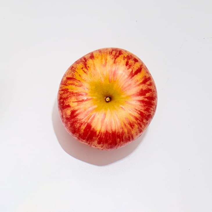 A honey crisp apple on a white surface.