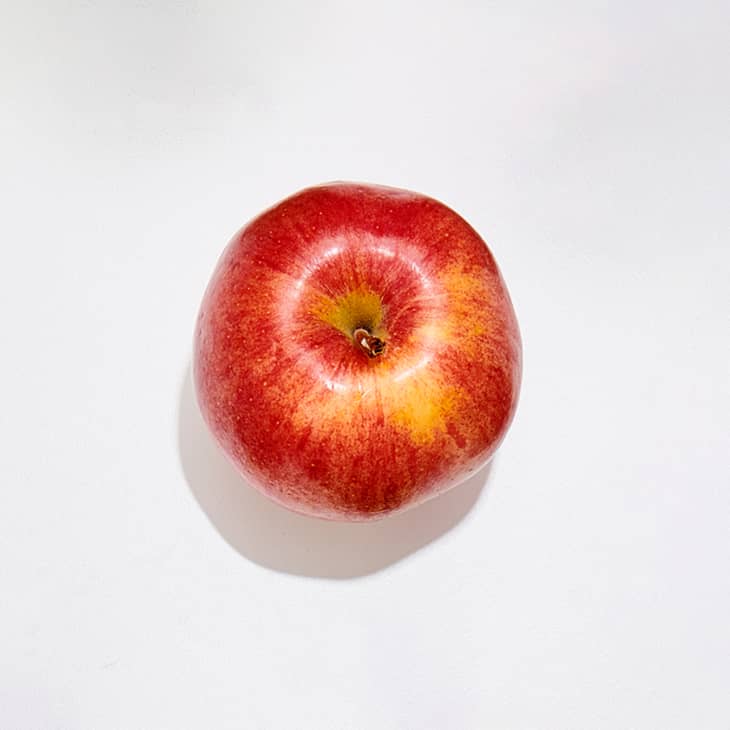 A sweetango apple on a white surface.