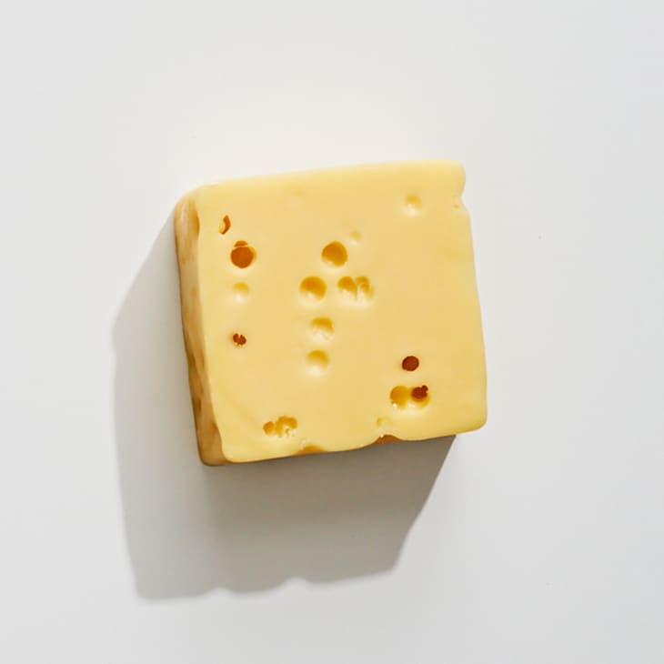 An overhead photo of alpine-style cheese on a white surface.