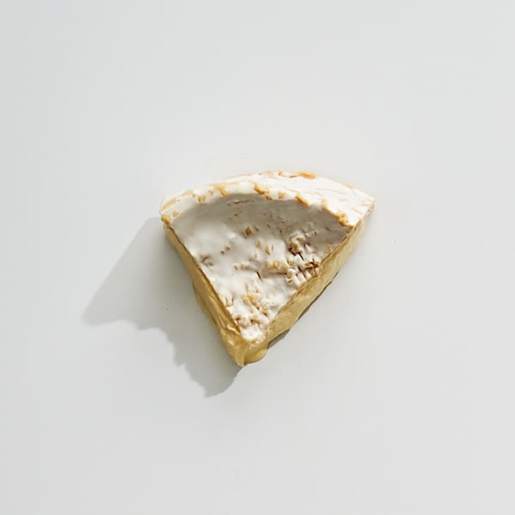 An overhead photo of bloomy rind triple cream cheese on a white surface.