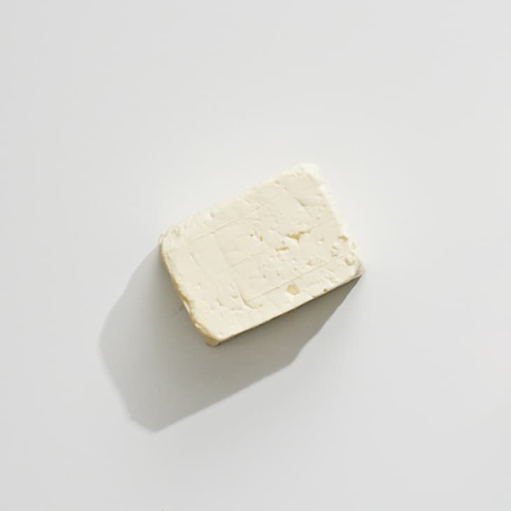 An overhead photo of feta cheese on a white surface.