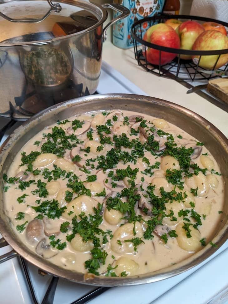 white sauce in sauce pan with gnocchi and parsley on top