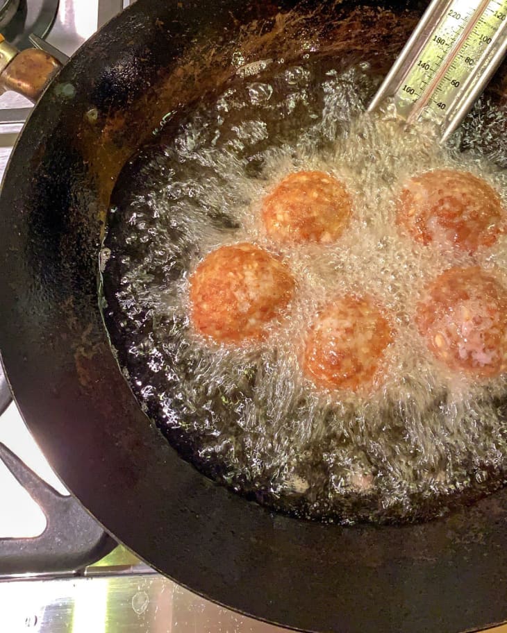 meatballs frying in a pan with a thermometer sticking out