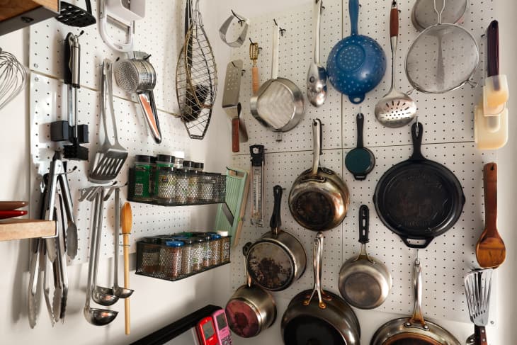 Organized pots and pans, spices on a pegboard in a kitchen