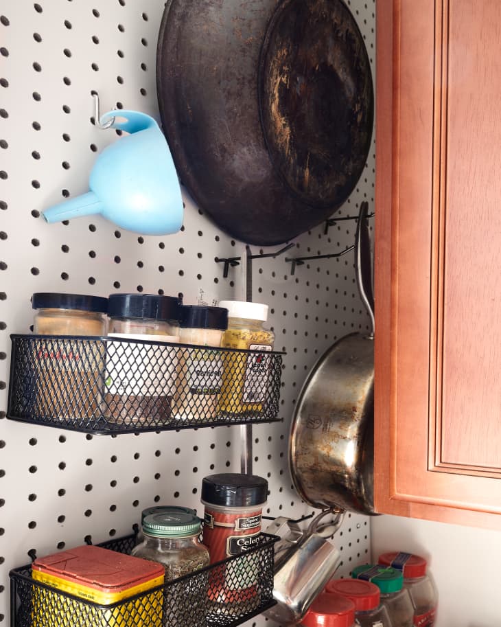 Organized kitchen pantry items, pots and pans, on pegboard