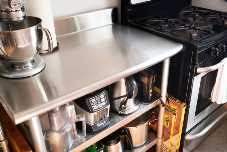 Organized kitchen appliances and pantry items on shelf next to oven