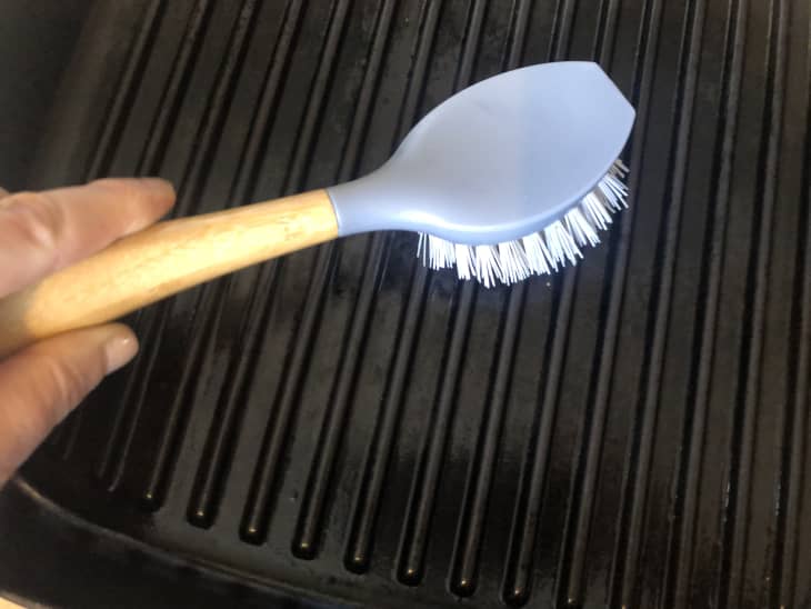 wood-handled scrub brush on grill pan
