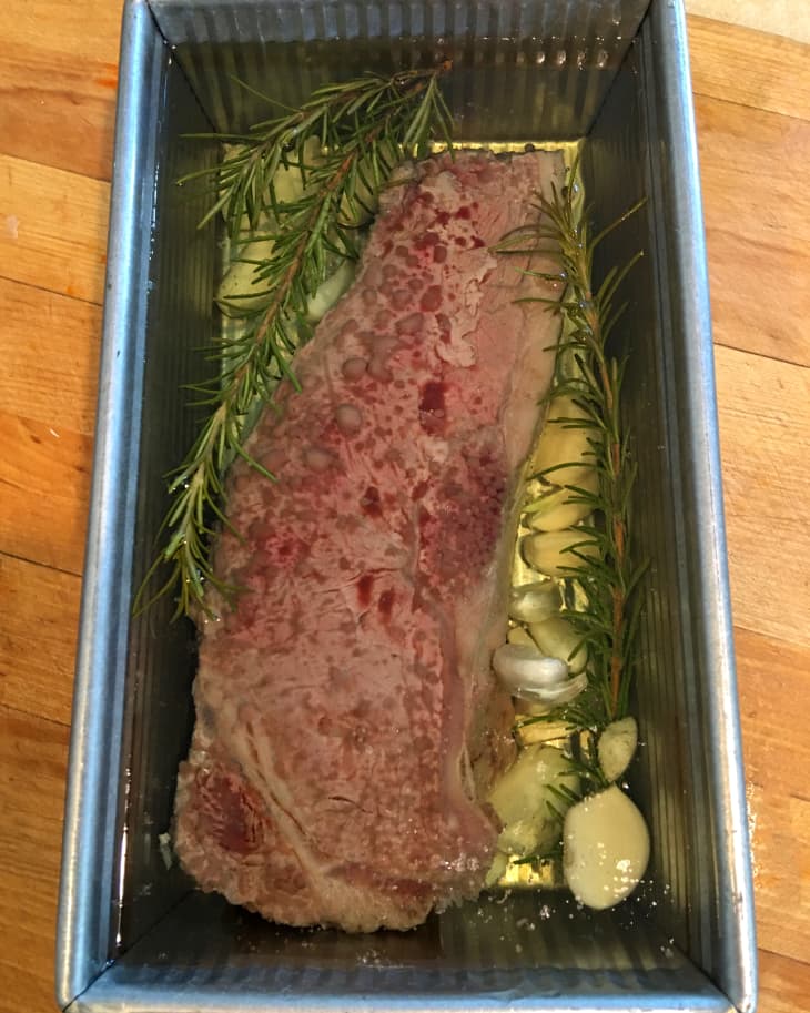 steak sits in an oil bath with garlic