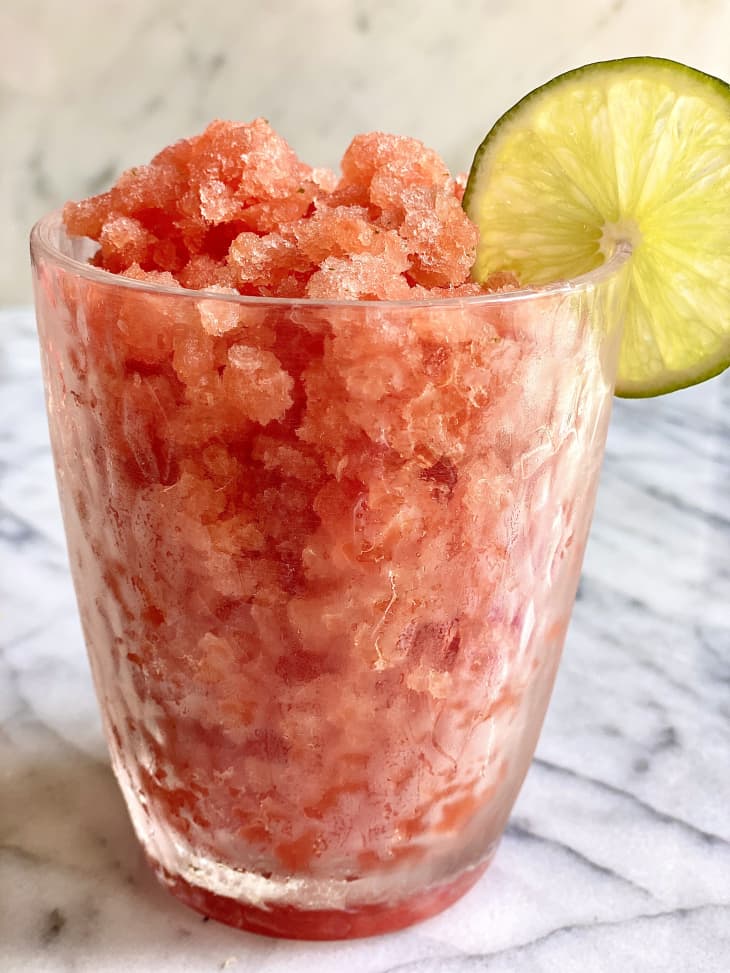 Photograph of watermelon granita in a glass cup with lime slice.