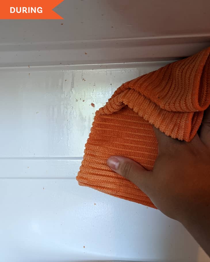 Hand using microfiber cloth to clean inside a microwave.