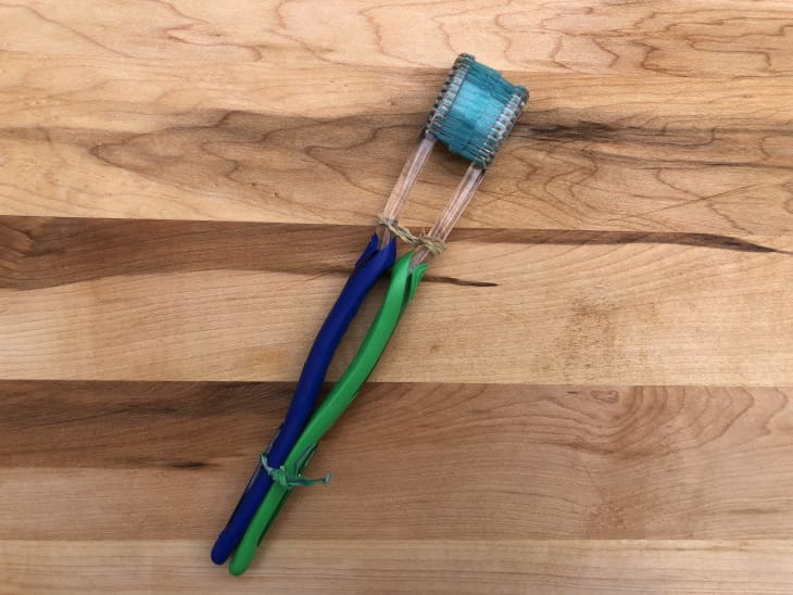two toothbrushes tied together with bristles facing each other