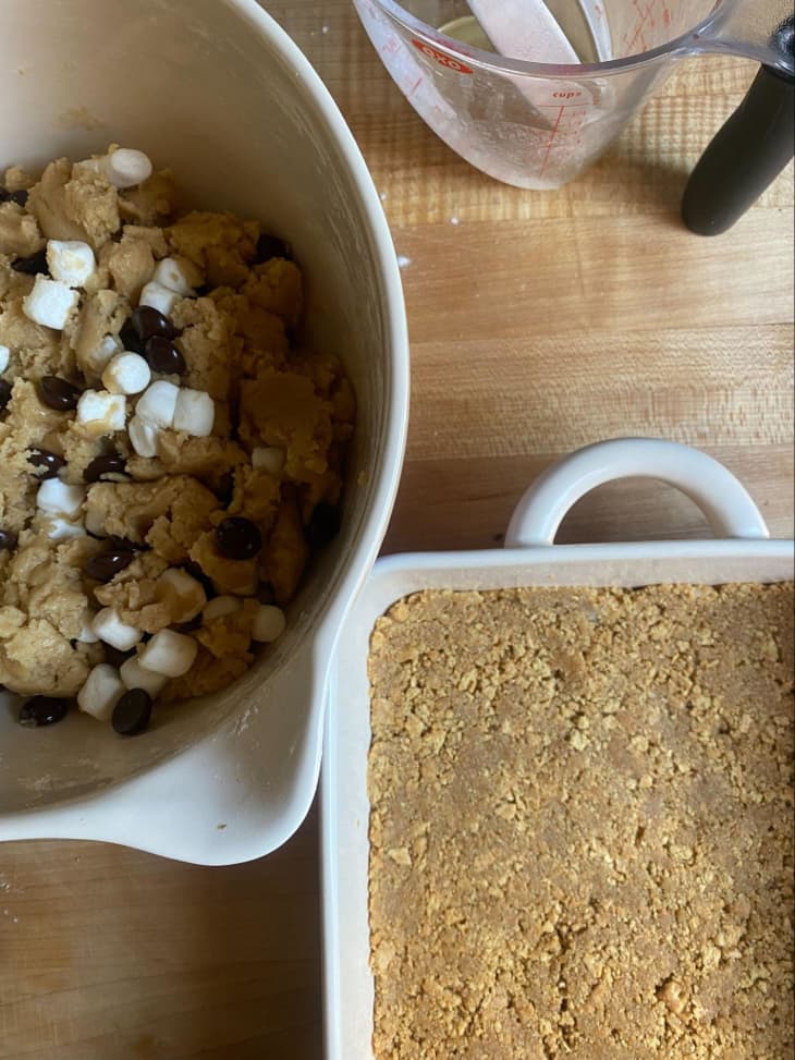 bowl with s'mores blondie batter next to square baking dish with graham cracker crust