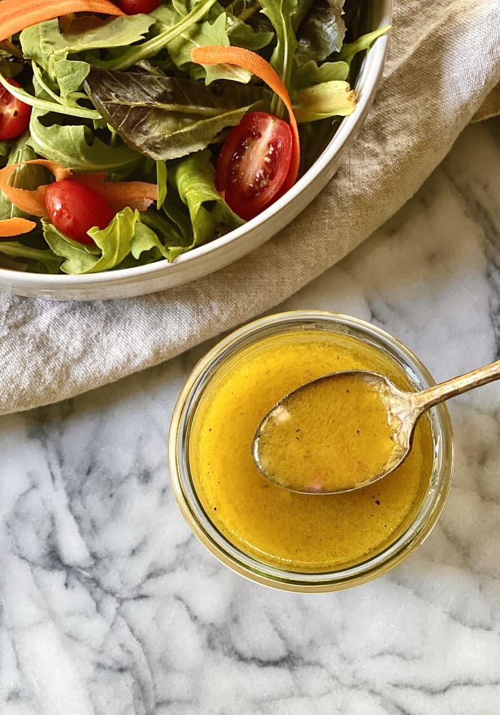 Photograph of champagne vinaigrette with a bowl of salad.