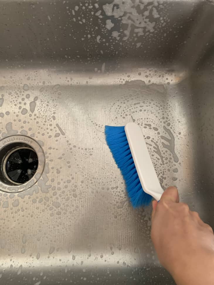 scrubbing the sink with a brush