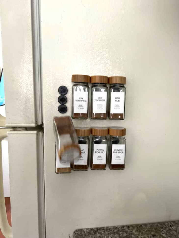 spice jars attached to refrigerator, one falling off