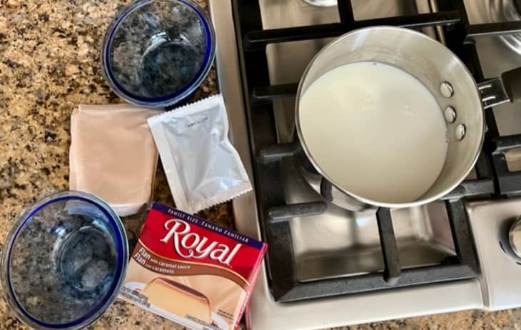 pot of milk on stovetop, bowls and contents of Royal flan box