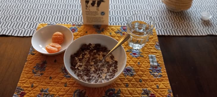 bowl of cereal, glass of water, orange segments