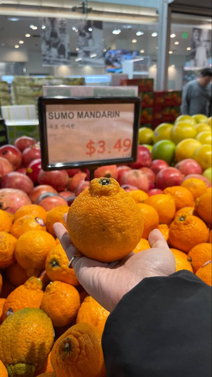 Someone holding Sumo mandarin at H-Mart.