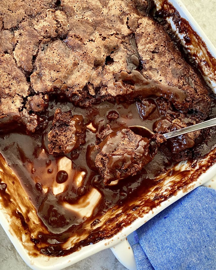 Chocolate cobbler in baking pan with a scoop out. Spoon in pan