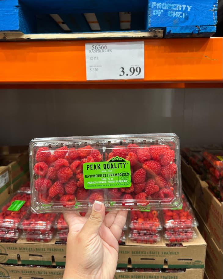 A container of Peak Quality Raspberries being held up for the camera in a Costco store