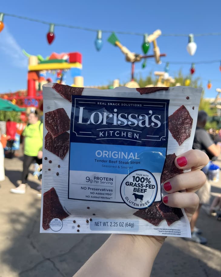 Someone holding up Lorissa's Kitchen Original Tender Beef Steak Strips at Disney