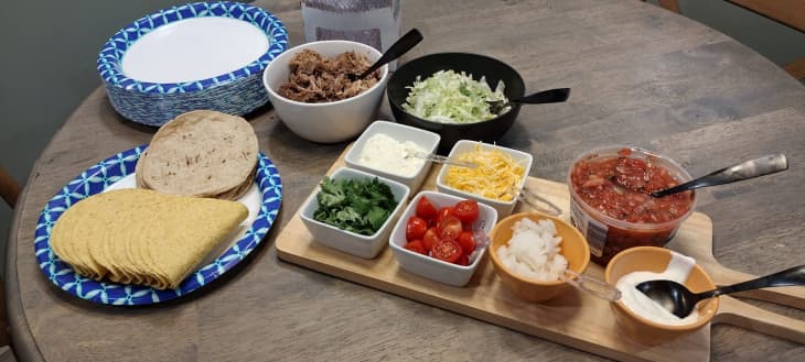 DIY taco bar with tortillas, lettuce, meat, tomatoes, cheese, sour cream, salsa, cilantro, onions
