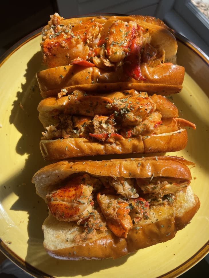 Several cooked lobster rolls on a plate.
