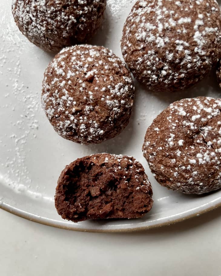 Chocolate macaroon cookies sprinkled with powdered sugar on white plate.