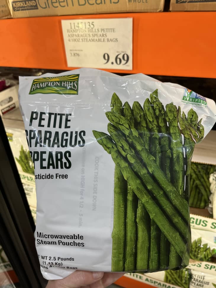 Someone holding package of asparagus spears.