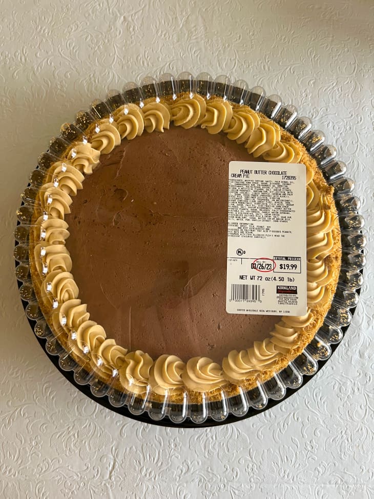 Costco Peanut Butter pie in plastic case on white surface.