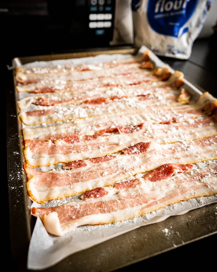 Bacon coated with flour on baking sheet.