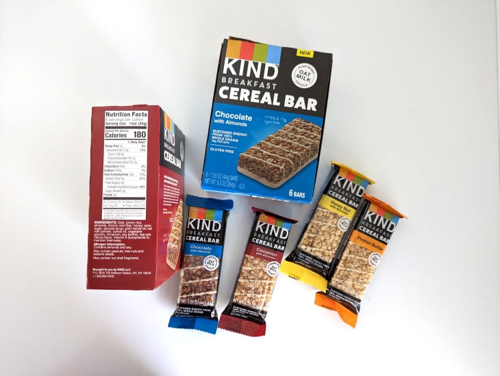 Various flavors of Kind cereal bars on white background.
