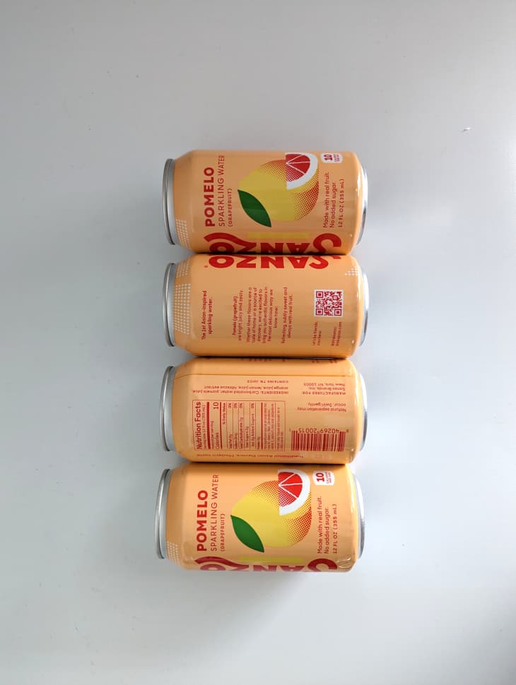 Cans of Pomelo soda lined up on white background.