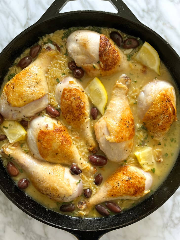 Chicken in skillet with broth, rice, lemons and olives before cooking.