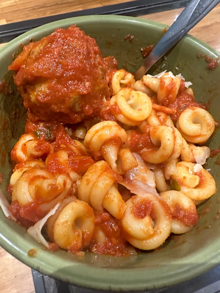 Sfoglini pasta in bowl with red sauce and meatball.