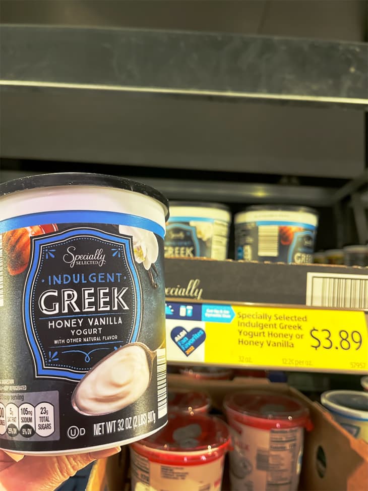 Someone holding container of Specially Selected Greek yogurt.