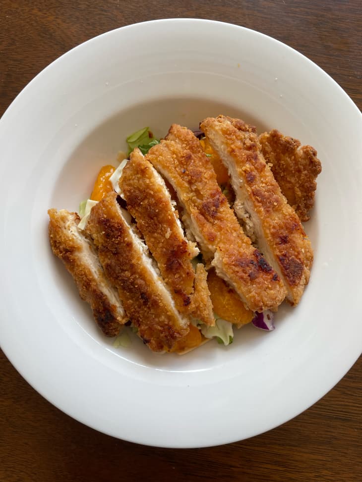 Three ingredient Aldi lunch salad with sliced breaded chicken breast on top.