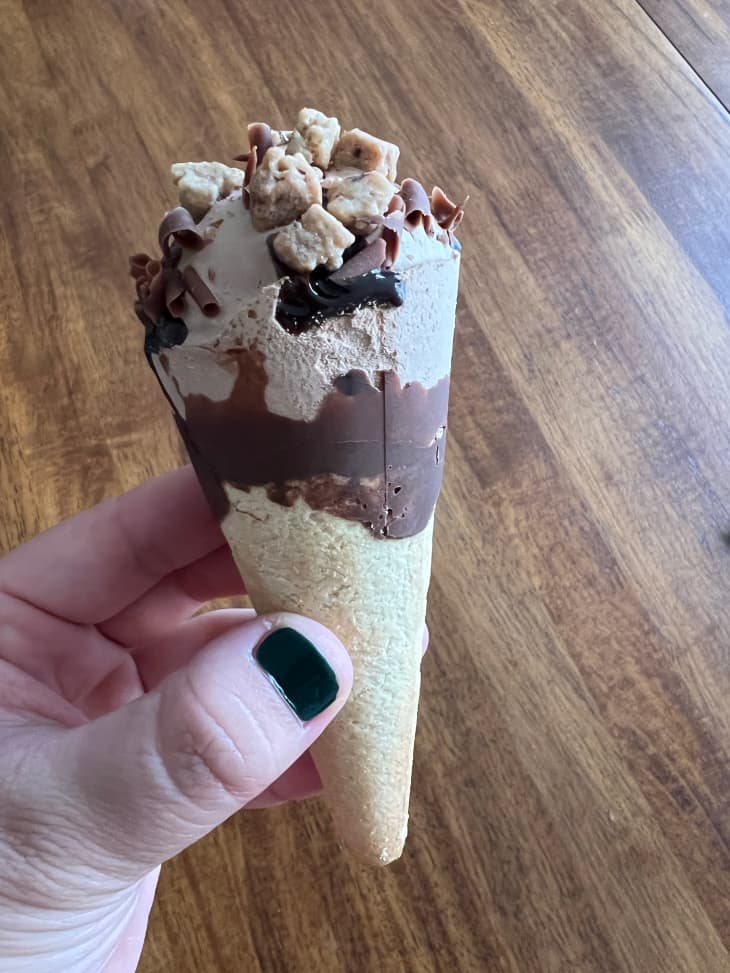 Someone holding Haagen-Dazs chocolate ice cream in a cone.