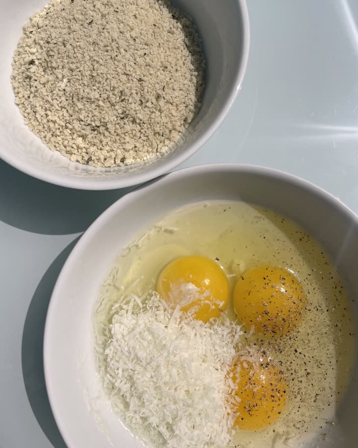 one bowl with raw eggs, parmesan cheese, another bowl of panko bread crumbs