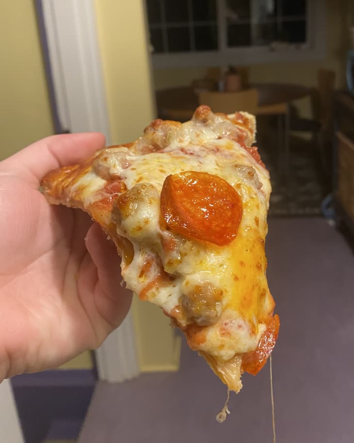 Chicago's Home Run Inn Pizza - photo of someone holding a sausage and pepperoni slice