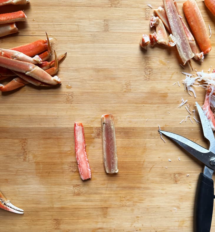 meat removed from crab legs on wood cutting board, kitchen shears nearby