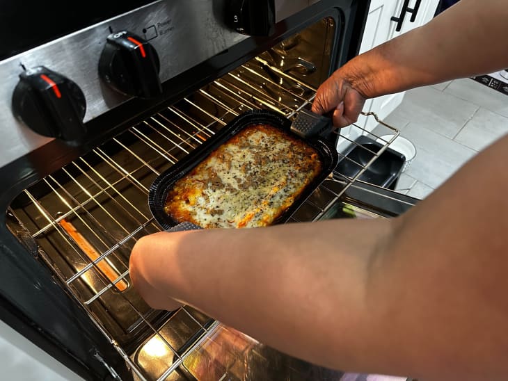 Someone using Dexas silicone oven mitts to grab a baked casserole out of the oven