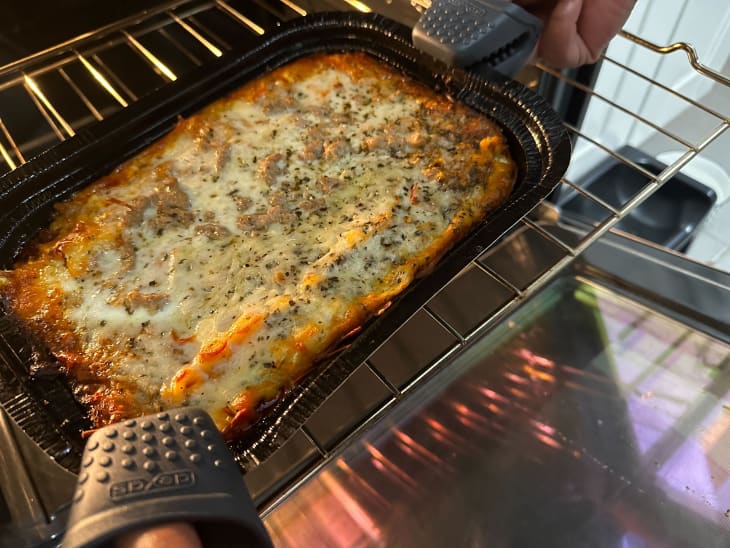 Someone using Dexas silicone oven mitts to grab a baked casserole out of the oven